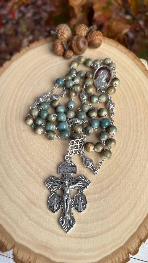 Handmade Padre Pio rosary with earth-colored ceramic beads, silver-tone chain, and ornate crucifix featuring Jesus and devotional medals.