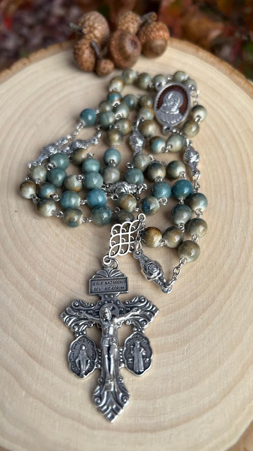 Devotional handmade rosary with Saint Pio centerpiece, silver chain links, and ornate crucifix flanked by Saint Benedict and Miraculous Medal.