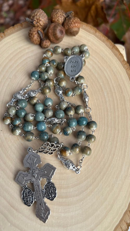 Catholic rosary honoring Saint Padre Pio, with round ceramic beads in green and brown tones and a detailed Italian crucifix centerpiece.