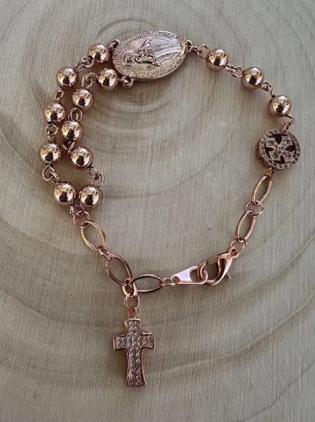 Rose gold rosary bracelet featuring polished prayer beads, Miraculous Medal centerpiece, and lobster clasp
