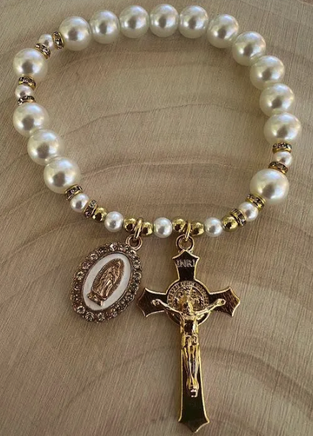 Handmade Catholic rosary bracelet with pearl beads, gold crucifix, and Our Lady of Guadalupe charm on wood background