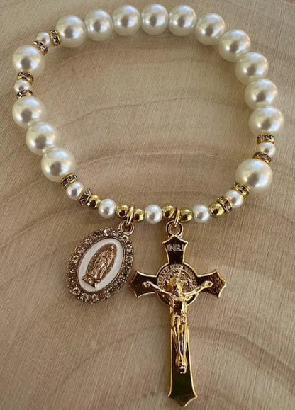 Handmade Catholic rosary bracelet with pearl beads, gold crucifix, and Our Lady of Guadalupe charm on wood background