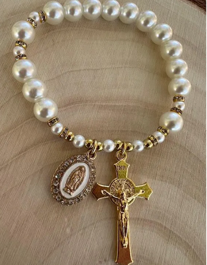 Catholic pearl bracelet with gold-tone Our Lady of Guadalupe medal and crucifix, displayed flat on wooden surface